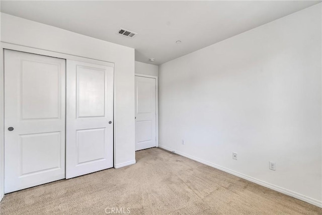 unfurnished bedroom with a closet and light colored carpet