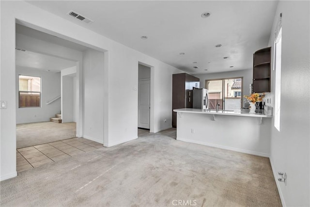 unfurnished living room with sink and light colored carpet