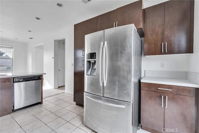 kitchen with dark brown cabinets, light tile patterned floors, and appliances with stainless steel finishes