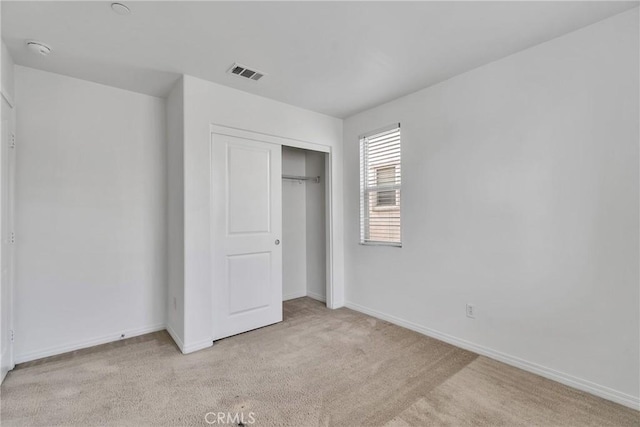 unfurnished bedroom featuring light colored carpet and a closet