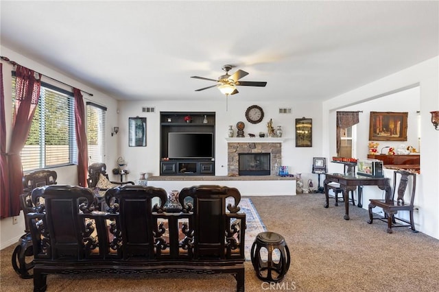 carpeted living room featuring a fireplace and ceiling fan