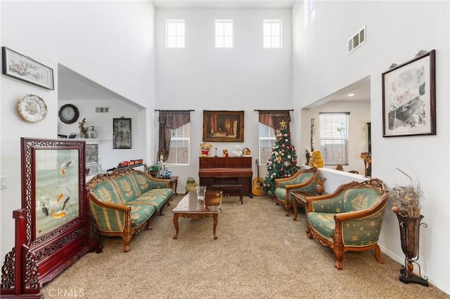 living area featuring plenty of natural light, carpet, and a high ceiling