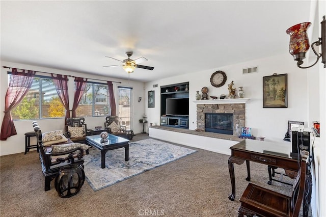 carpeted living room featuring a fireplace and ceiling fan