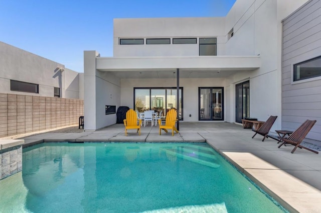 back of property with a fenced in pool, a patio area, fence, and stucco siding