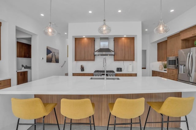 kitchen with appliances with stainless steel finishes, light countertops, a large island, and wall chimney exhaust hood