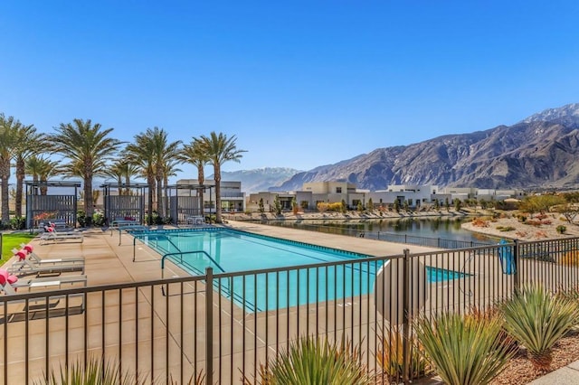 community pool with a patio area, fence, and a mountain view