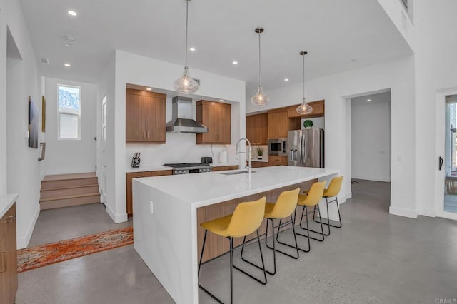 kitchen with stainless steel appliances, light countertops, wall chimney range hood, and finished concrete flooring