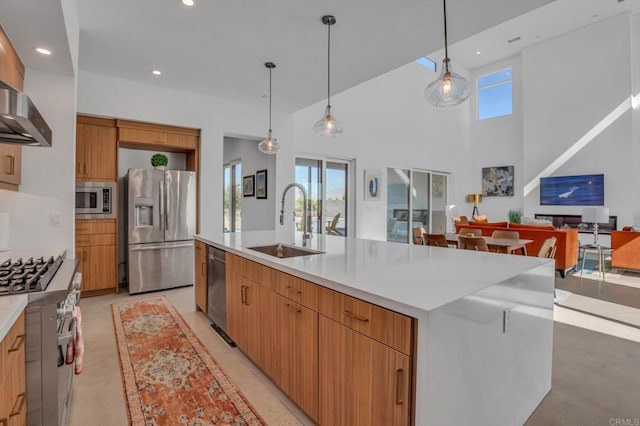 kitchen with appliances with stainless steel finishes, a sink, a large island with sink, and decorative light fixtures