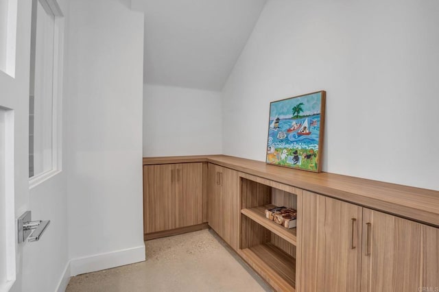 interior space featuring lofted ceiling and finished concrete floors