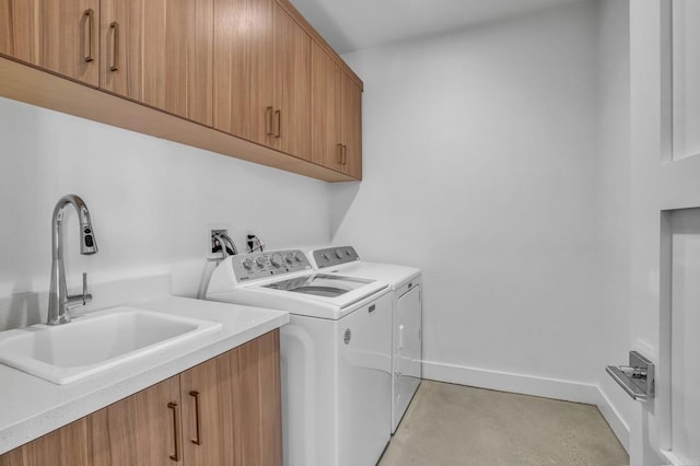 laundry area featuring baseboards, cabinet space, independent washer and dryer, and a sink