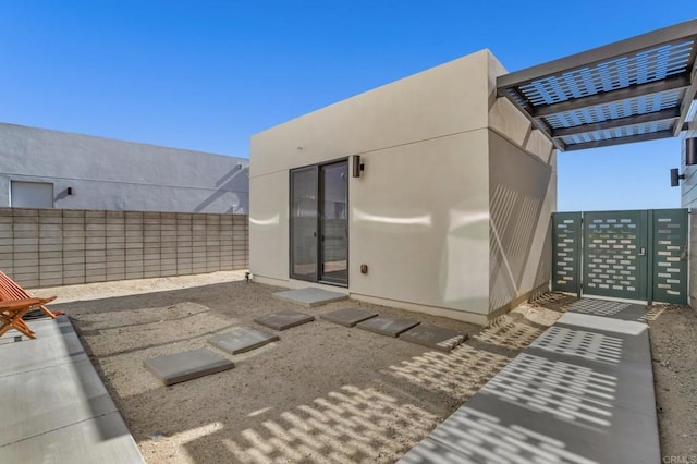 rear view of property featuring fence private yard, a gate, and stucco siding