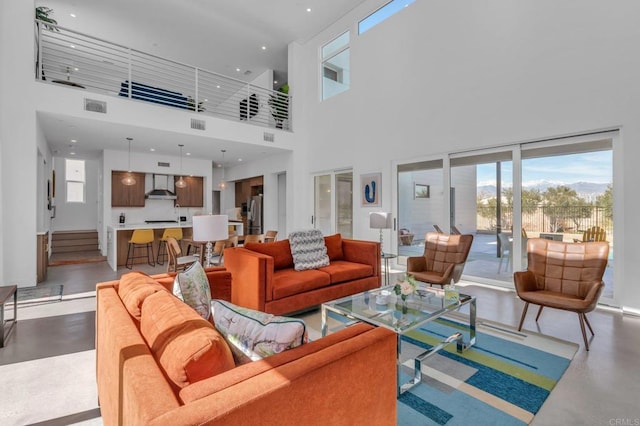 living area featuring stairway, visible vents, concrete floors, and a towering ceiling