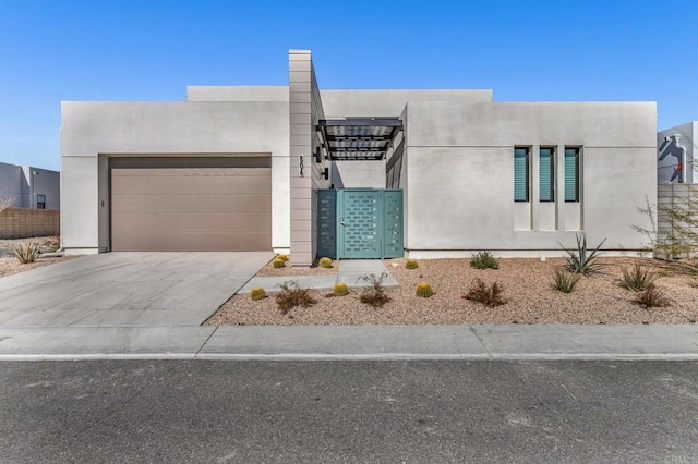 adobe home featuring concrete driveway, an attached garage, and stucco siding