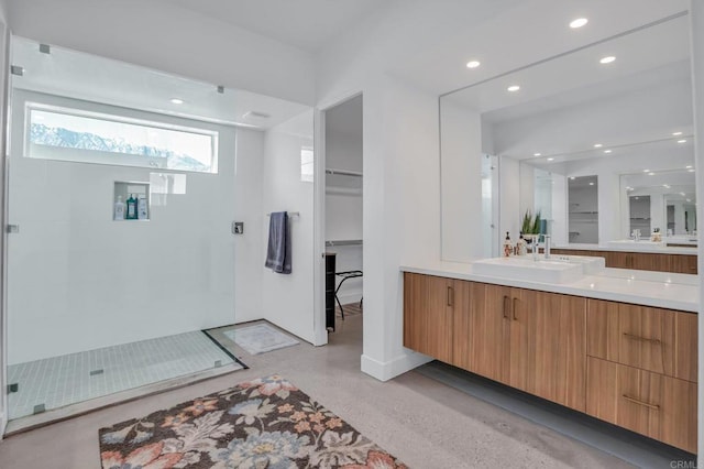 bathroom with a walk in closet, finished concrete flooring, recessed lighting, a stall shower, and vanity