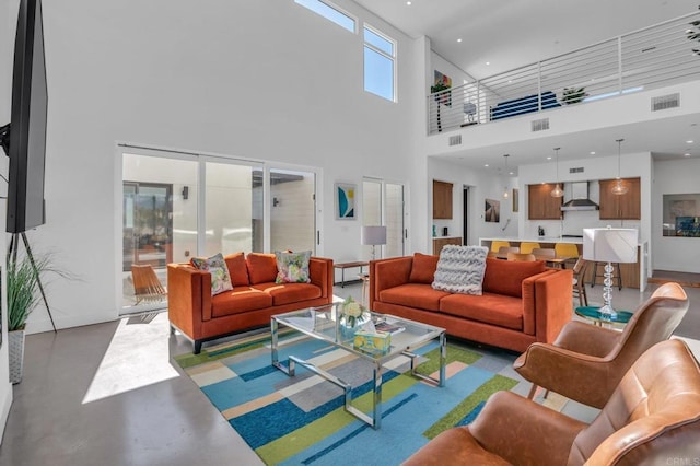 living room with a towering ceiling, visible vents, and finished concrete floors