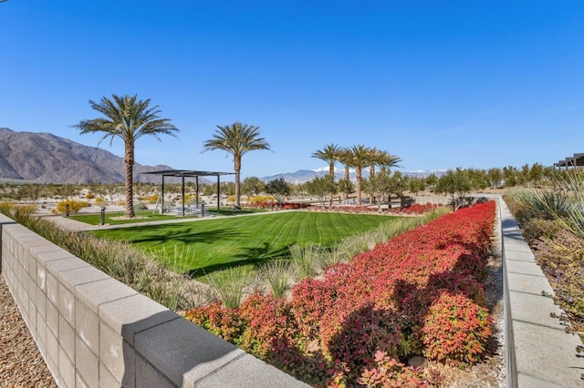 view of property's community featuring a pergola, a mountain view, and a lawn