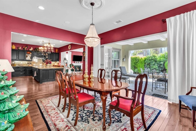 dining room with beam ceiling, dark wood-type flooring, and a chandelier