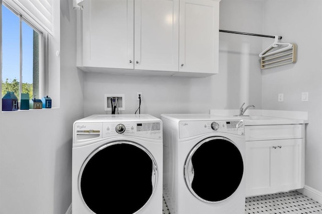 clothes washing area featuring washer and clothes dryer, cabinets, and sink