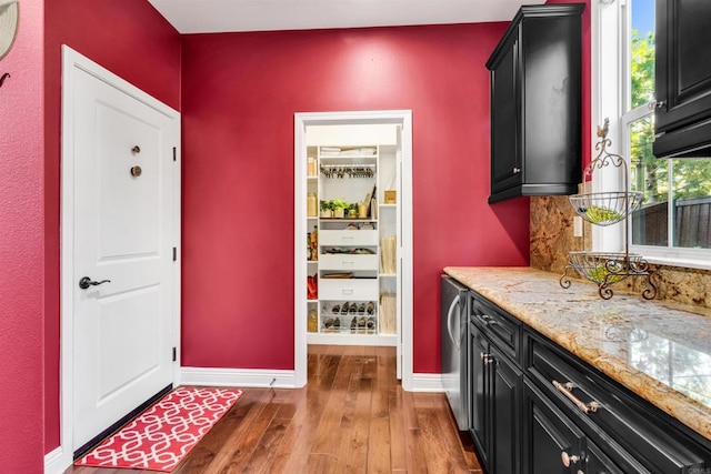 interior space featuring stainless steel refrigerator, light stone counters, and wood-type flooring