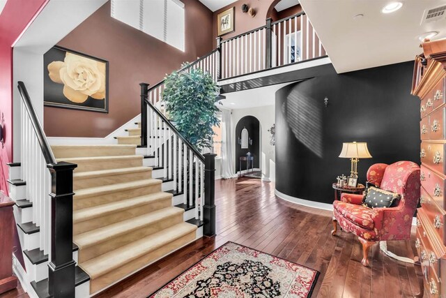 foyer entrance featuring a towering ceiling and dark wood-type flooring