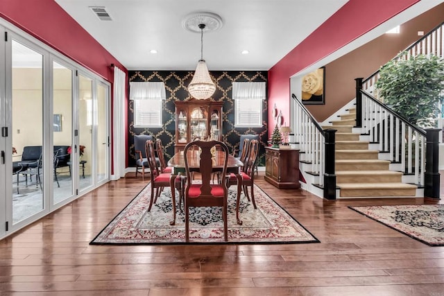 dining space featuring hardwood / wood-style floors, french doors, and an inviting chandelier