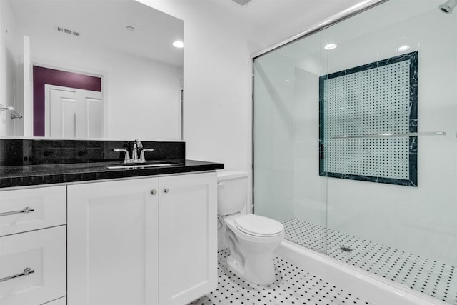 bathroom featuring toilet, vanity, and tiled shower