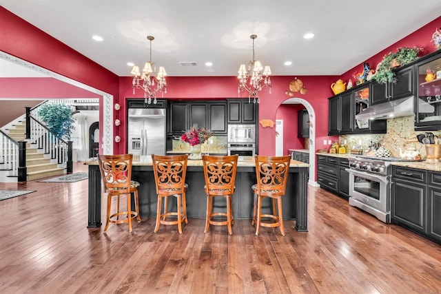 kitchen with a center island, stainless steel appliances, backsplash, decorative light fixtures, and light wood-type flooring