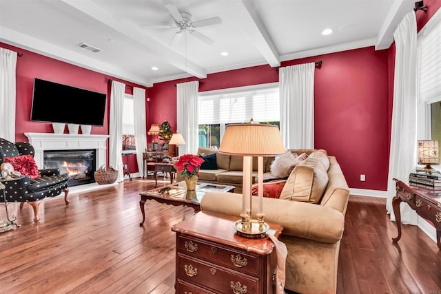 living room featuring beam ceiling, hardwood / wood-style flooring, ceiling fan, and crown molding