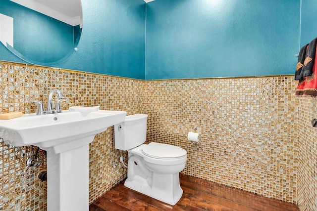 bathroom featuring sink, hardwood / wood-style floors, tile walls, and toilet