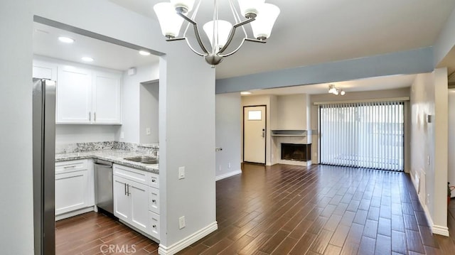 kitchen with hanging light fixtures, light stone counters, dark hardwood / wood-style flooring, white cabinets, and appliances with stainless steel finishes