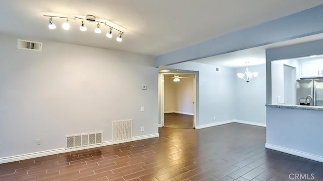 unfurnished living room featuring dark hardwood / wood-style floors and ceiling fan with notable chandelier