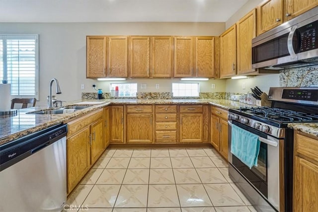 kitchen with sink, light stone countertops, stainless steel appliances, and light tile patterned floors