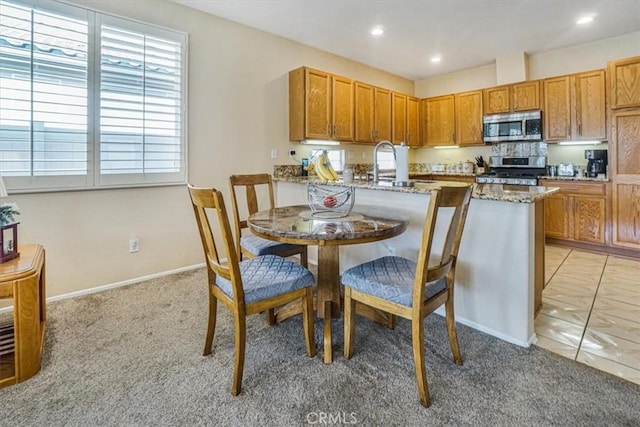 kitchen with light stone countertops, sink, light colored carpet, and appliances with stainless steel finishes