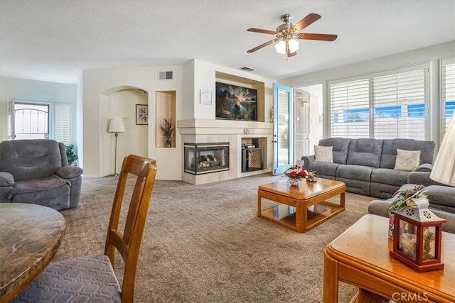 carpeted living room featuring a tile fireplace and ceiling fan