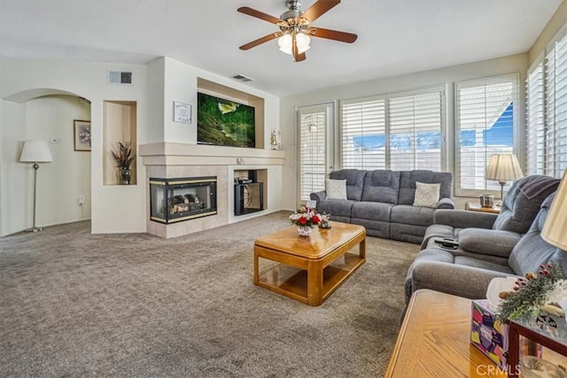 living room with carpet flooring, a tiled fireplace, and ceiling fan