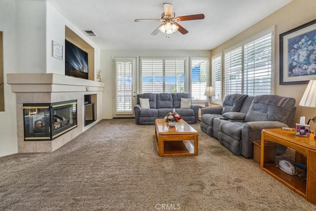 carpeted living room with ceiling fan and a tile fireplace