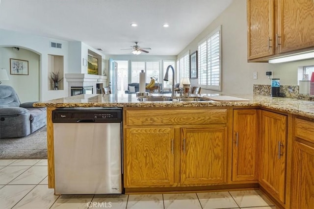 kitchen with ceiling fan, dishwasher, sink, light stone counters, and kitchen peninsula