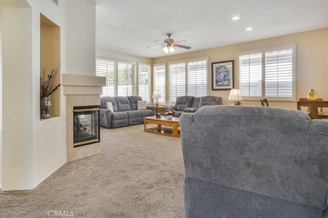 carpeted living room with a tile fireplace and ceiling fan