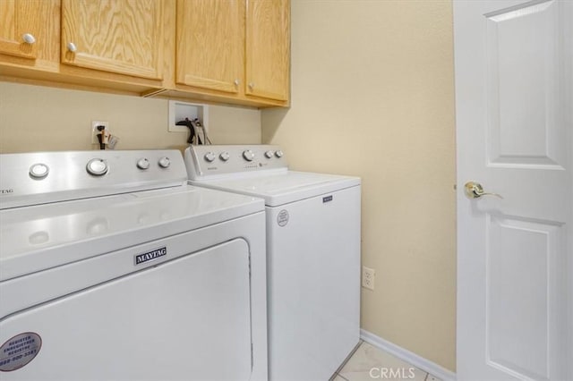 laundry area featuring cabinets, light tile patterned floors, and washing machine and clothes dryer