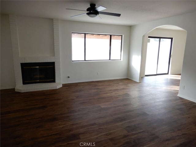 unfurnished living room with ceiling fan, a fireplace, and dark hardwood / wood-style floors