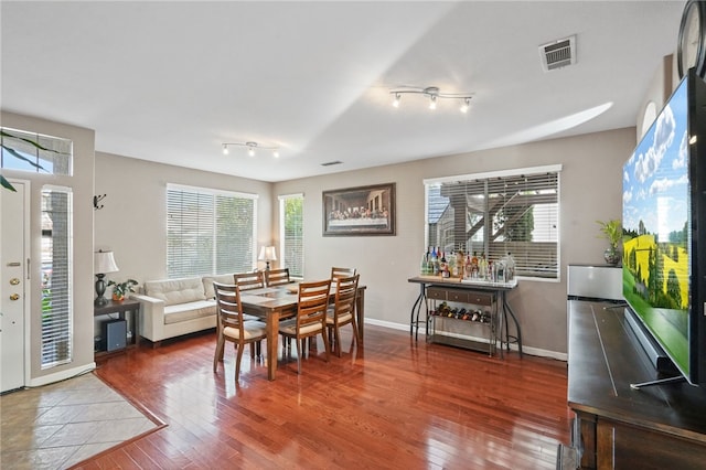 dining room with hardwood / wood-style floors and track lighting