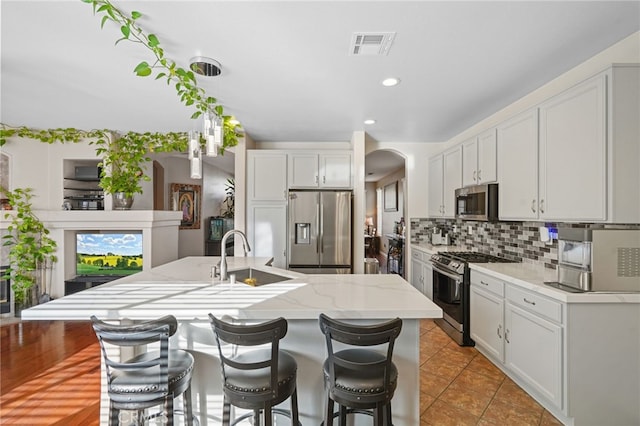 kitchen featuring a kitchen island with sink, sink, white cabinets, and stainless steel appliances