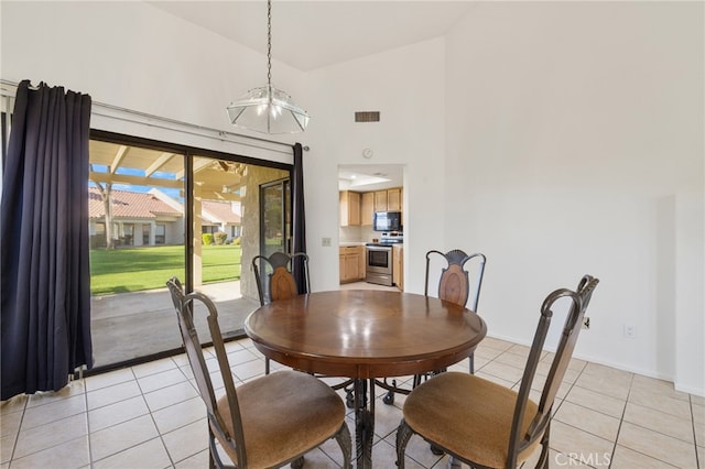 dining space featuring light tile patterned flooring, high vaulted ceiling, and an inviting chandelier