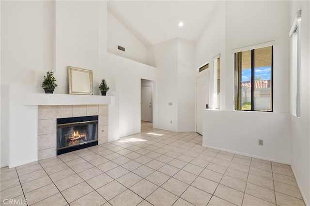 unfurnished living room with light tile patterned floors, high vaulted ceiling, and a tiled fireplace