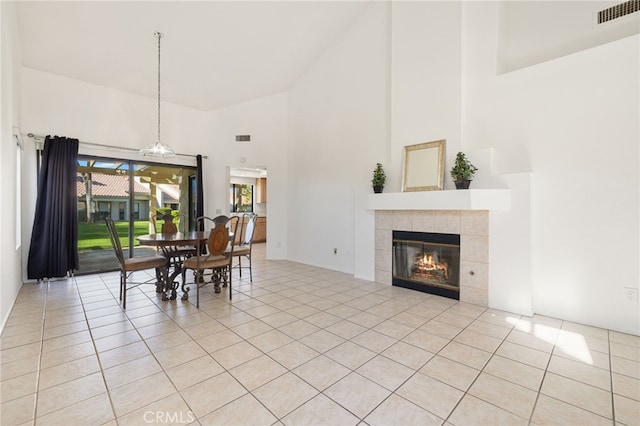 dining area featuring a towering ceiling, light tile patterned floors, and a tiled fireplace