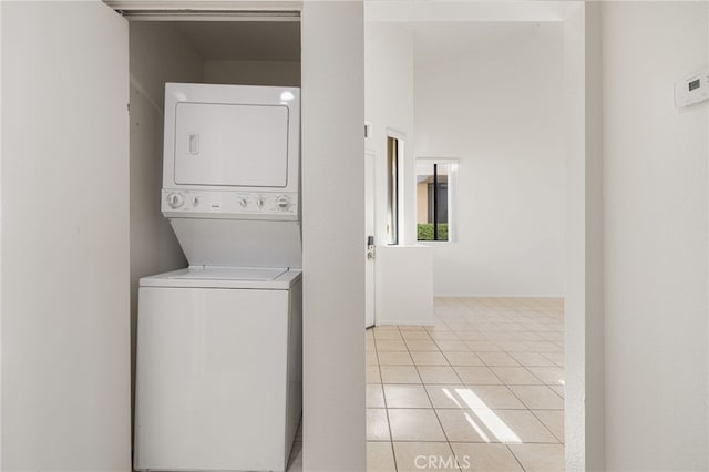 laundry area featuring light tile patterned floors, stacked washer / drying machine, and laundry area