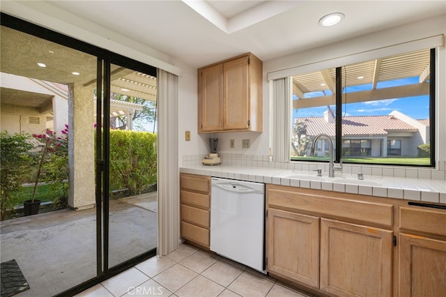 kitchen with tile countertops, a wealth of natural light, dishwasher, and light tile patterned floors