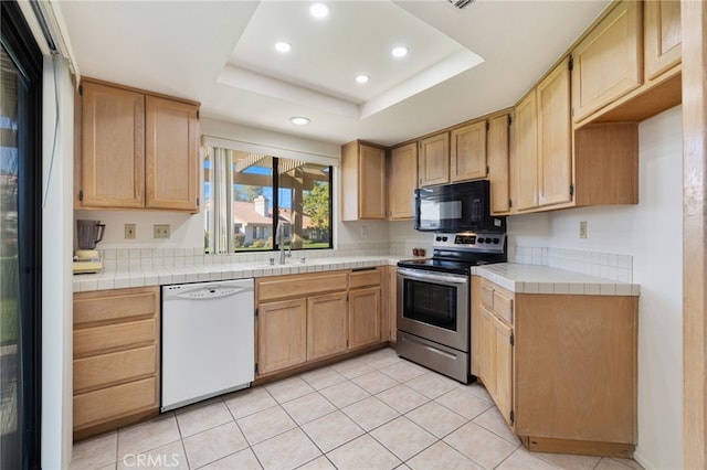 kitchen featuring white dishwasher, tile counters, stainless steel electric range oven, and a tray ceiling