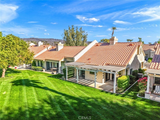 rear view of property with a pergola, a patio, and a lawn