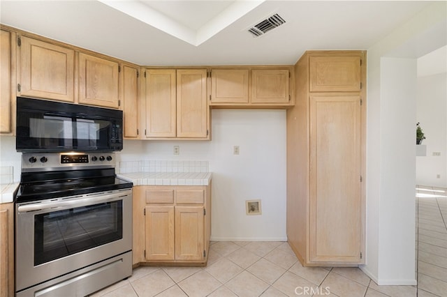 kitchen with light brown cabinets, tile countertops, stainless steel range with electric cooktop, and light tile patterned flooring